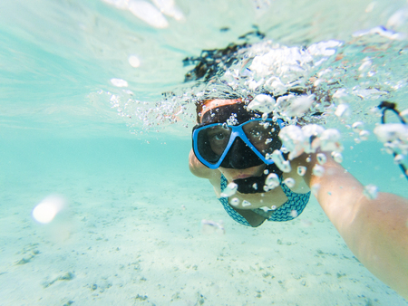 woman taking an underwater selfie while snorkeling in crystal clear tropical waterの写真素材