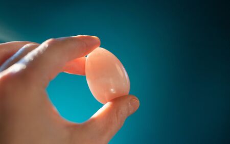 woman holding a pink quartz yoni egg