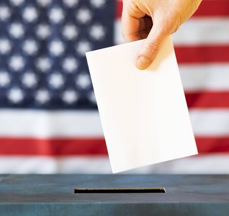 usa elections  the hand of woman putting her vote in the ballot boxの写真素材