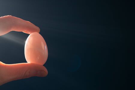 woman holding a pink quartz yoni egg