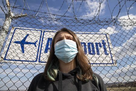 coronavirus global fight concept - COVID-19 - woman wearing face mask and airport sign