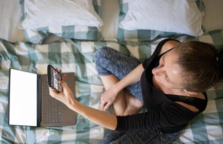 woman using laptop or tablet in bed white empty screen for copy space