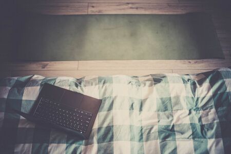 laptop on bed and yoga mat mental health at home