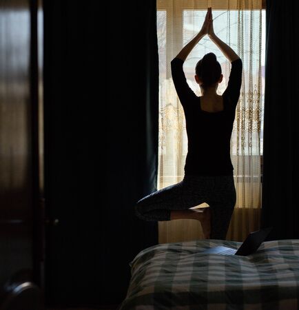 woman in a yoga pose in bedroom staying fit and mentally healthy at homeの写真素材