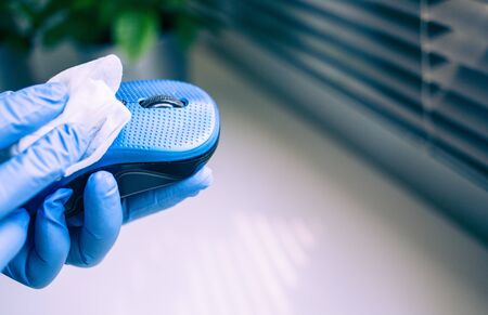 Office sanitizing wipe wiping mouse and mousepad with disinfecting wipes. Coronavirus COVID-19 sanitize cleaning disinfection of work desk.の写真素材