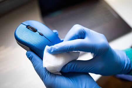 Office sanitizing wipe wiping mouse and mousepad with disinfecting wipes. Coronavirus COVID-19 sanitize cleaning disinfection of work desk.の写真素材