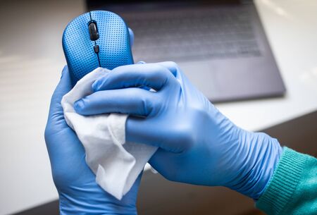 Office sanitizing wipe wiping mouse and mousepad with disinfecting wipes. Coronavirus COVID-19 sanitize cleaning disinfection of work desk.の写真素材
