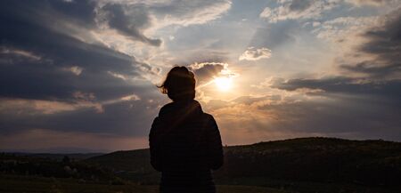 panorama woman head looking at sun breaking through clouds at sunset