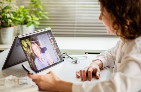 telemedicine concept elderly woman using laptop and taking her blood pressureの写真素材