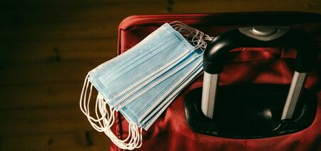 medical masks on a red suitcase safe travel after the pandemicの写真素材