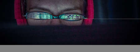 hacker at computer data reflecting in eyeglassesの写真素材