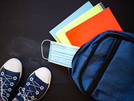 back to school concept during pandemic top view of sneakers backpack mask clockの写真素材