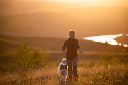 happy woman with white dog in autumn landscapeの写真素材