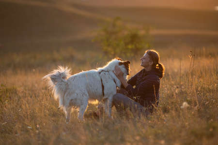 happy woman with white dog in autumn landscapeの写真素材
