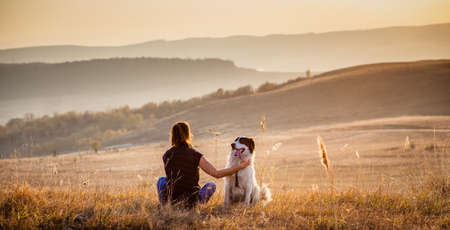 woman with dog relaxing in autumn landscape