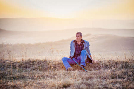 active senior man relaxing in autumn landscape after trekkingの写真素材
