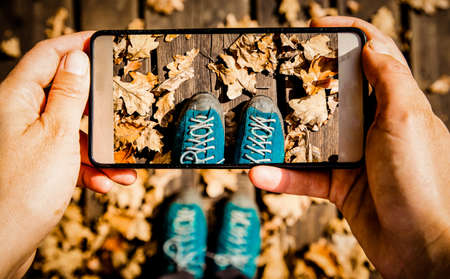 taking a picture of her trekking shoes and fall foliage