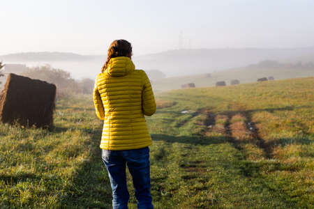 woman walking alone in autumn landscape  social distancing