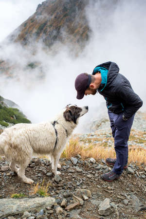 handsome man and his dog trekking in high mountains