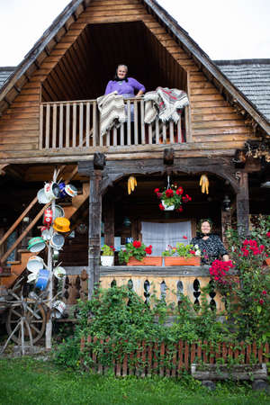 BREB, ROMANIA - 11 OCTOBER 2020: Two elderly women standing on the porch of a traditional wooden house in Maramures.のeditorial素材