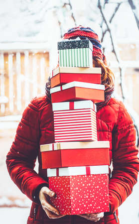 woman returning home from shopping holding pile of christmas present boxes