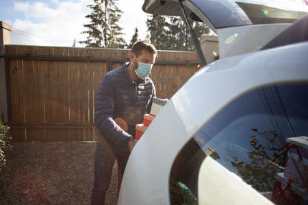 man packing Christmas gift boxes in car