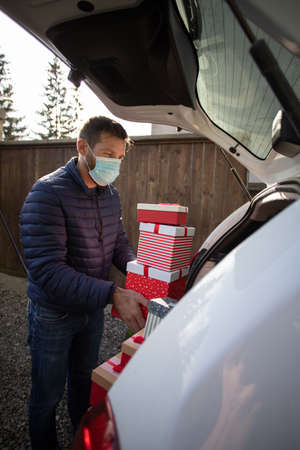 man packing Christmas gift boxes in car