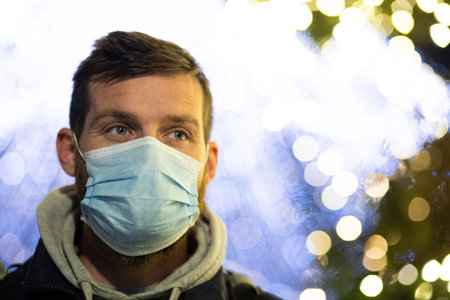 man wearing mask on  the street Christmas lightsの写真素材