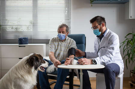 doctor consulting elderly male patient at home dog in foreground
