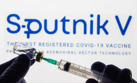 CLUJ-NAPOCA -ROMANIA - MARCH 9 2021: Sputnik Vaccine Covid-19 concept. Syringe needle and vaccine, blurred Sputnik V company logo on the background.のeditorial素材