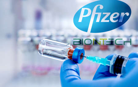 CLUJ-NAPOCA -ROMANIA - MARCH 9 2021: Pfizer vaccine Covid-19 concept. Syringe needle and vaccine, blurred Pfizer company logo on the background.のeditorial素材