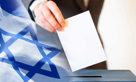 elections in Israel. Hand of a woman putting her vote in the ballot box. Waved Israel flag on background.の写真素材