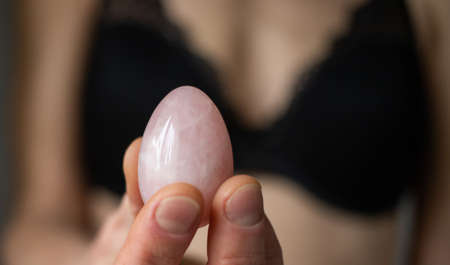woman holding in hand a vaginal (yoni) egg. Rose quartz crystal jade egg.の写真素材