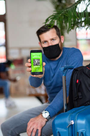 health Vaccine Passport for Coronavirus or Covid-19. Traveller Using Mobile Phone with Vaccination in Immune Status to Certificated International Traveling in train stationの写真素材