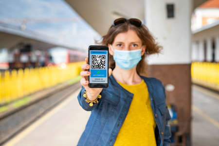 health Vaccine Passport for Coronavirus or Covid-19. Traveller Using Mobile Phone with Vaccination in Immune Status to Certificated International Traveling in train stationの写真素材
