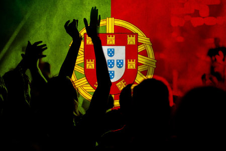 football fans supporting Portugal - crowd celebrating in stadium with raised hands against Portugal flagの写真素材
