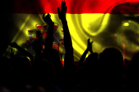 football fans supporting Spain- crowd celebrating in stadium with raised hands against Spanish flag