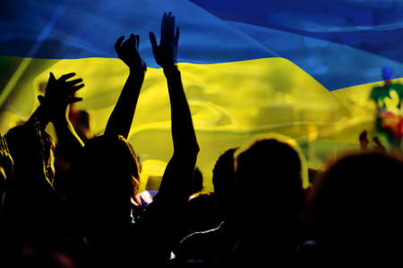 football fans supporting Ukraine - crowd celebrating in stadium with raised hands against Ukraine...