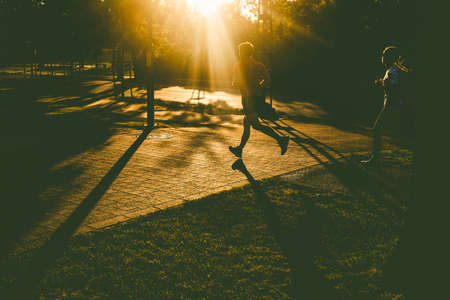 silhouette of person running in park at sunset healthy active lifestyleの写真素材