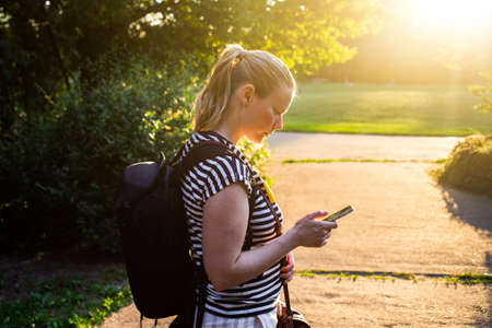 young woman using smartphone in park at sunset