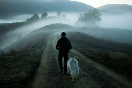 man walking in a foggy autumn landscapeの写真素材