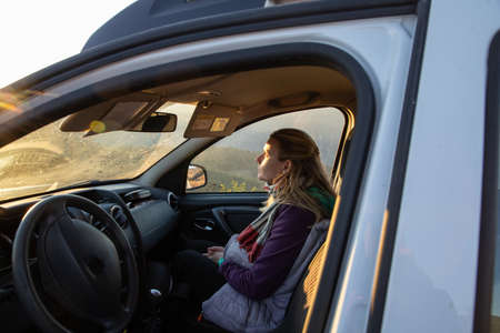 blonde woman in car at sunset autumn road trip