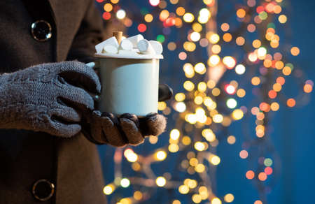 woman holding mug with mulled wine or hot chocolate at christmas market