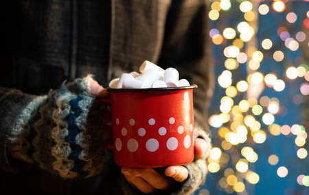 woman holding mug with mulled wine or hot chocolate at christmas marketの写真素材