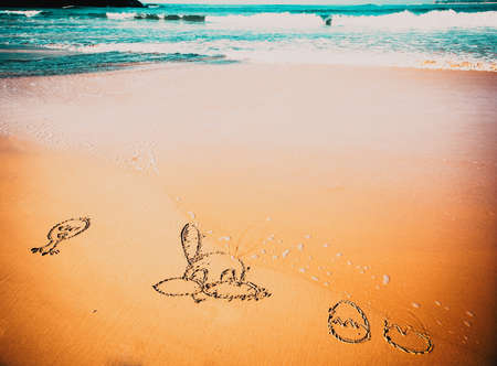 easter bunny and eggs in the sand by the seasideの写真素材