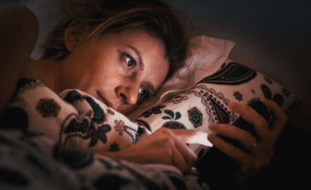 woman using smartphone in bed insomnia