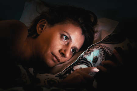 woman using smartphone in bed insomnia