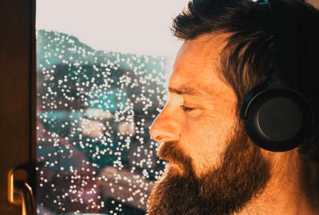 handsome adult man looking out on window on rainy day mental health