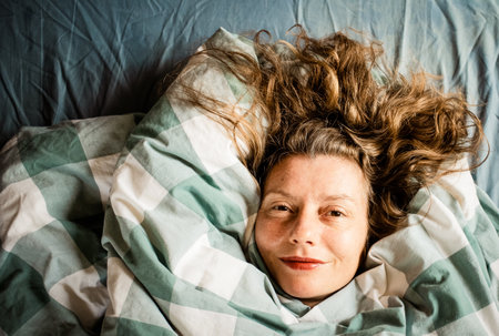 happy relaxed woman portrait sleeping in duvetの写真素材