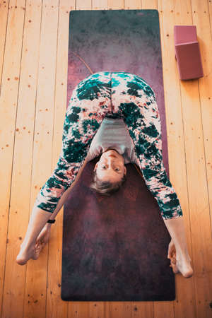 top view of woman doing yoga at home in Halasana or plough poseの写真素材